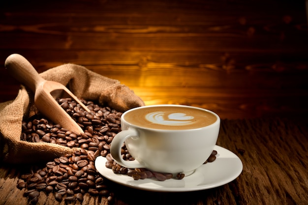 Taza de café con leche y granos de café sobre fondo de madera vieja