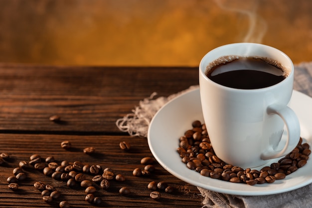 Taza de café con leche y granos de café sobre fondo de madera
