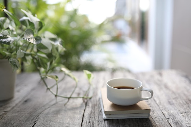 Taza de café con leche y libros con perlas y pothos de jade.