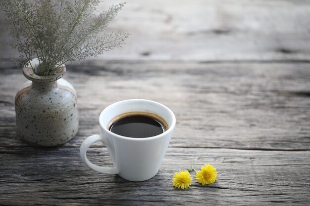 Taza de café con leche con maceta de flores secas en la mesa de madera rústica