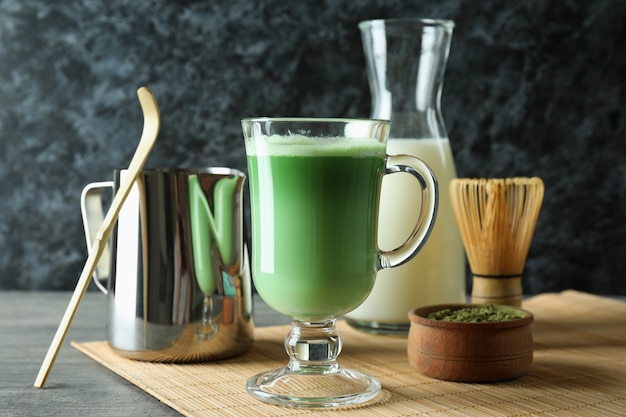 Taza de café con leche matcha y accesorios para hacer en mesa con textura gris