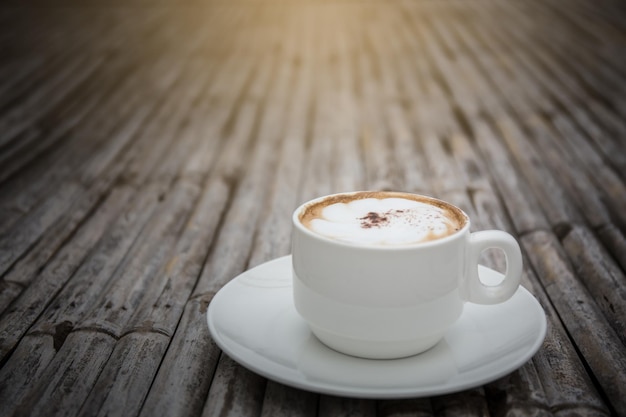 taza de café con leche en la mesa de madera de bambú.