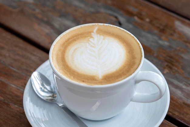 Taza de café con leche en la mesa de madera de cerca