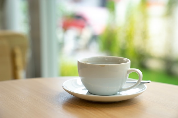 taza de café con leche en la mesa de madera con fondo de cafetería.