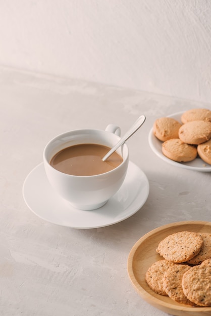 Taza de café con leche o capuchino con galletas sobre fondo de piedra clara