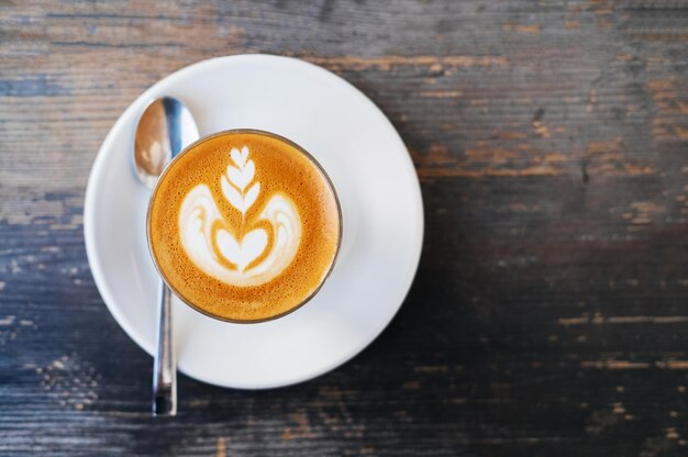 Taza de café con leche plana en una mesa de madera