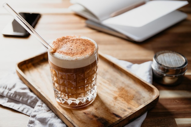 Taza de café con leche servido con tubo de vidrio en un escritorio de madera Concepto de pausa para el café