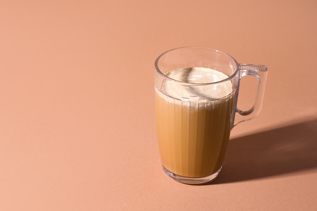 Taza de café con leche sobre un fondo marrón