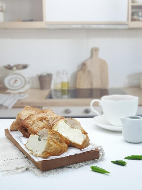 Una taza de café con leche y una tabla de cortar de madera con pan