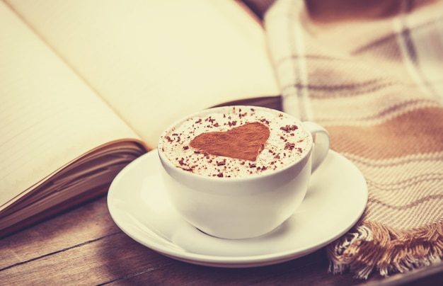 Taza de café y libro con bufanda.