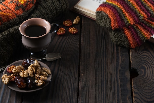 Taza de café, libro, gorro de lana y guantes sobre una mesa de madera