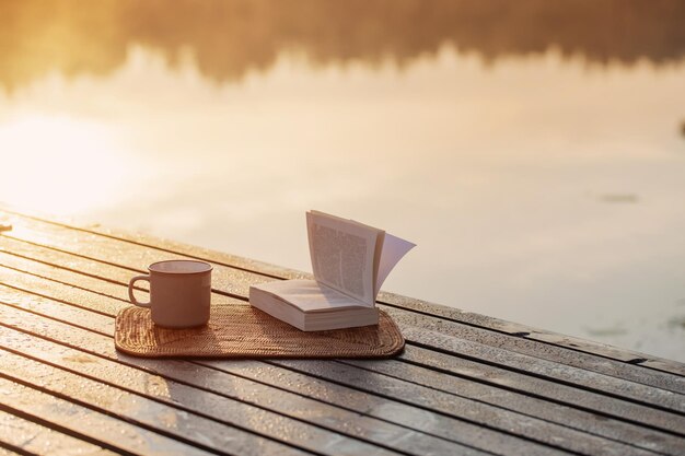 taza de café y libro en el muelle de madera en el lago de verano