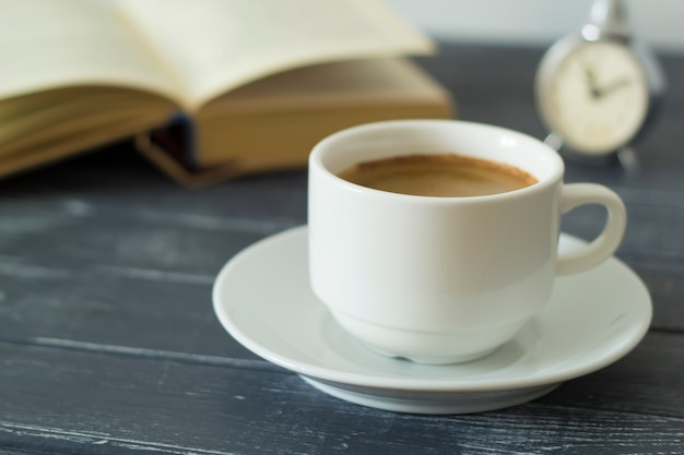 Una taza de café, un libro, un reloj: un ambiente acogedor para leer. Educación.