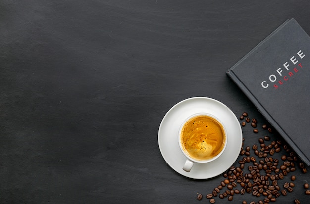 Taza de café y libro sobre fondo de piso de madera negra. vista superior. espacio para texto