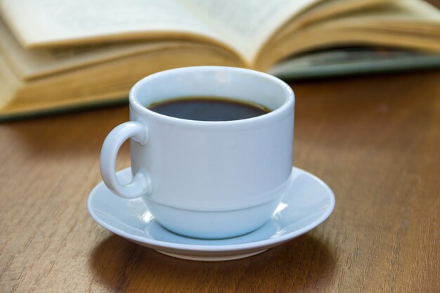 Taza de café y libro sobre mesa de madera