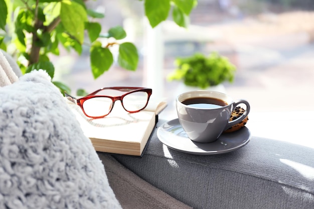 Taza de café con libro en el sofá en la habitación