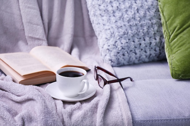 Taza de café con libro en el sofá en la habitación