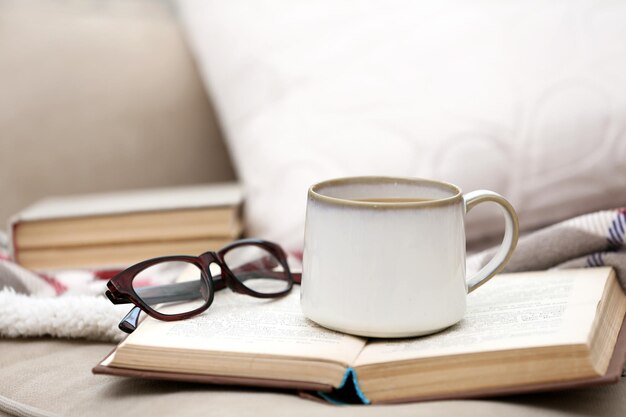 Taza de café con libro en el sofá en el salón