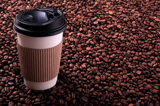 Taza de café para llevar con fondo de frijoles tostados