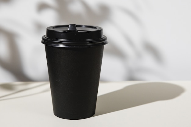 Taza de café para llevar con sombras de follaje, espacio de copia