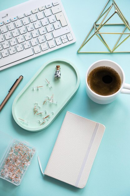 Taza de café en el lugar de trabajo azul pastel de Lady freelancer's home y teclado de computadora en la mesa