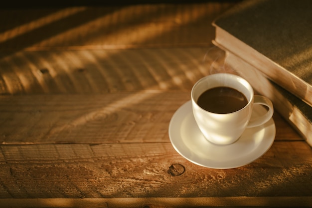 Taza de café con luz y sombra sobre madera vieja, mañana con café