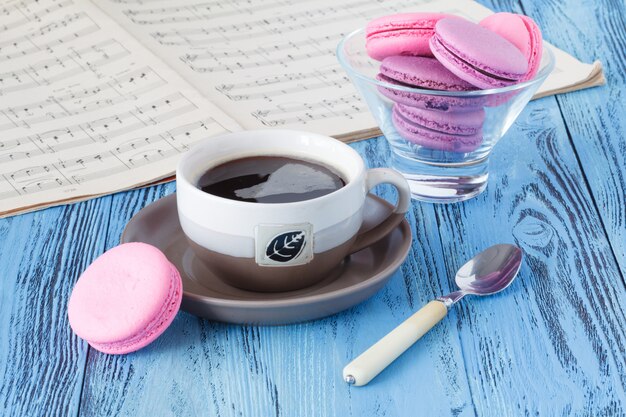 Taza de café con macarrones y notas musicales.