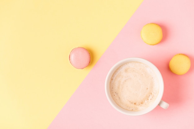 Taza de café con macarrones sobre fondo pastel