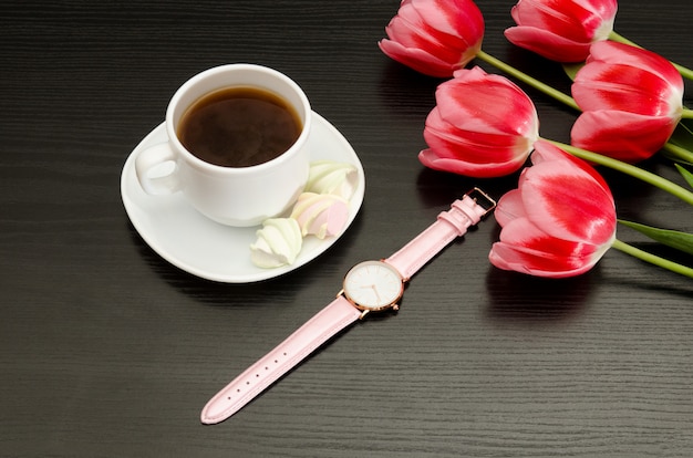 Taza con café y malvavisco, reloj, tulipanes rosados.