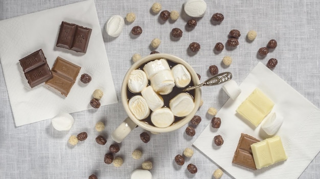 Una taza de café con malvaviscos y chocolate sobre un fondo blanco. Vista superior