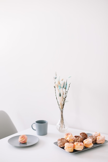 Taza de café con malvaviscos y flores sobre la mesa