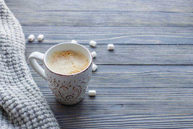 Taza de café con malvaviscos sobre un fondo de madera