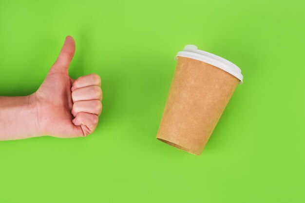 Taza de café y mano en forma de símbolo de aprobación en la mano sobre fondo verde. concepto de cero residuos