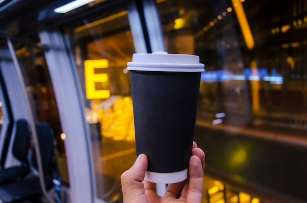 Taza de café en la mano del hombre del aeropuerto con taza negra