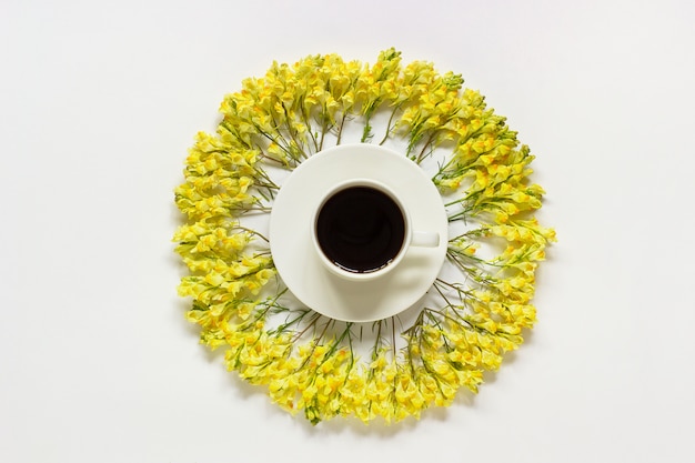 Taza de café y marco circular amarillo flores silvestres sobre fondo gris