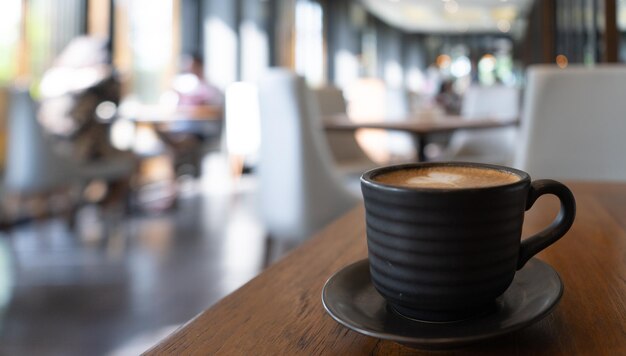 Foto taza de café en la mesa con café de fondo borroso