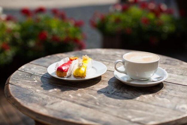 Una taza de café en la mesa y un delicioso eclair en un plato