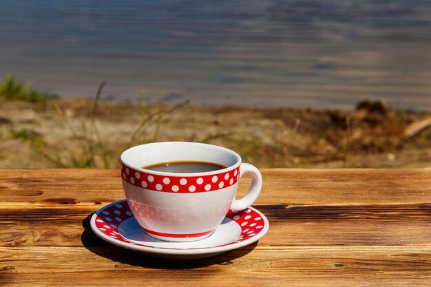 Taza de café en la mesa de madera cerca del río.