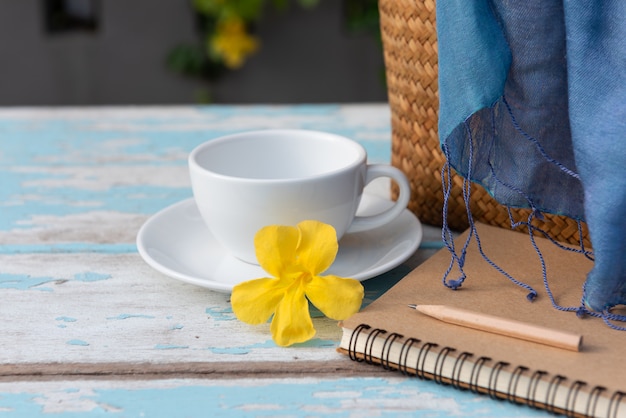 Taza de café en la mesa de madera con cuaderno de notas marrón