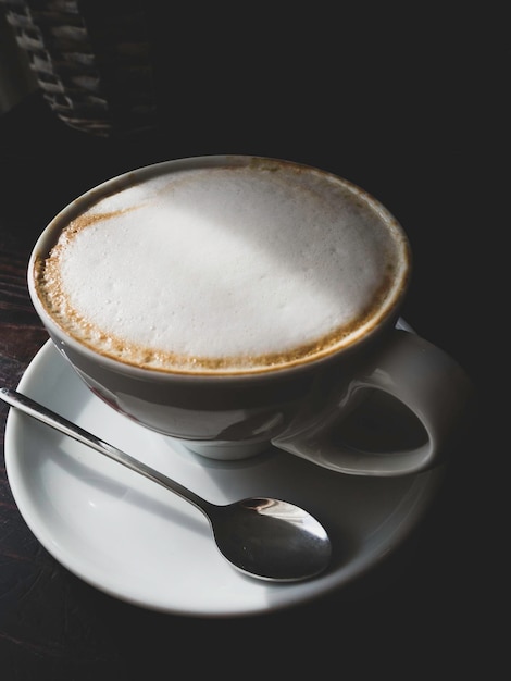 Taza de café en la mesa de madera con espuma de café con leche Café de la calle en la cafetería Vista superior