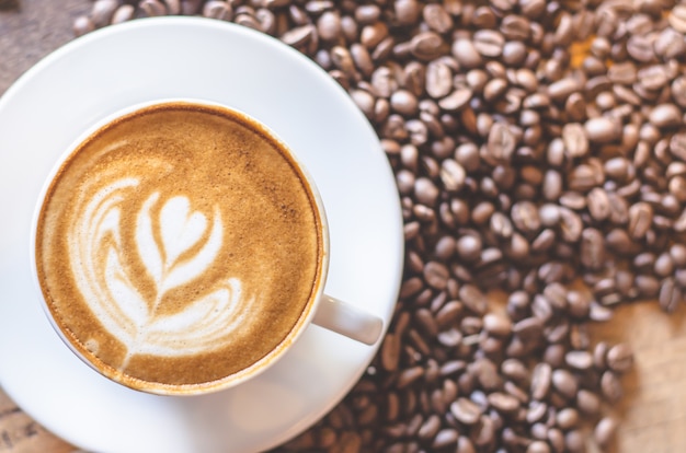 Taza de café en la mesa de madera con grano de café