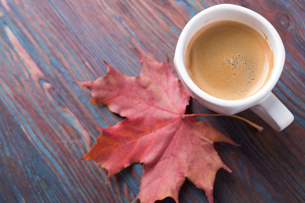 Una taza de café en la mesa de madera con hojas caídas. Copyspace