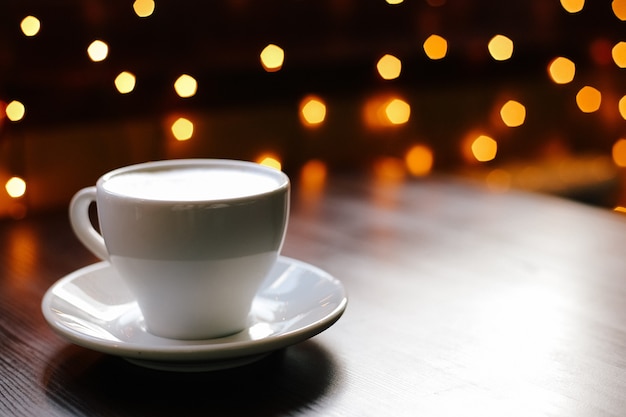 Foto una taza de café en la mesa de madera con luces en el fondo