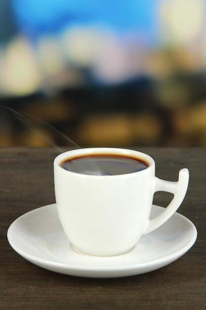 Foto taza de café en la mesa de madera sobre fondo brillante