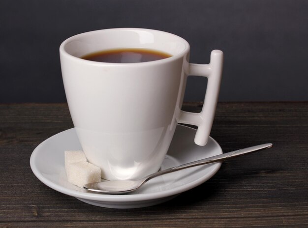 Taza de café en la mesa de madera sobre fondo gris