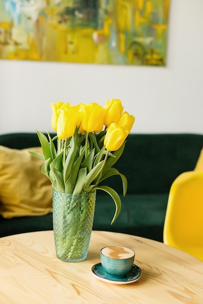 Taza de café en la mesa con tulipanes amarillos en el fondo