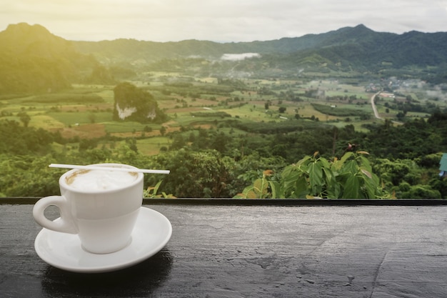 Taza de café en la mesa con vistas a la montaña en la mañana como fondo