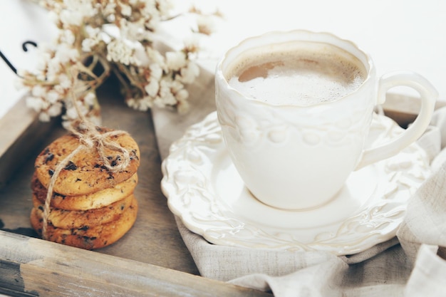 Taza de café y montón de sabrosas galletas con migas de chocolate en bandeja de madera