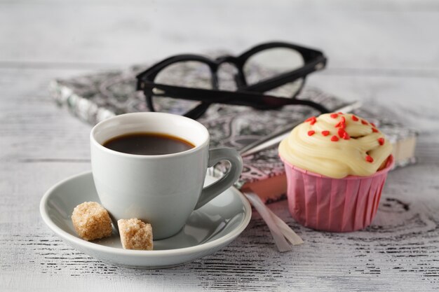 Taza de café y muffins en la mesa de oficina al comienzo de la jornada laboral