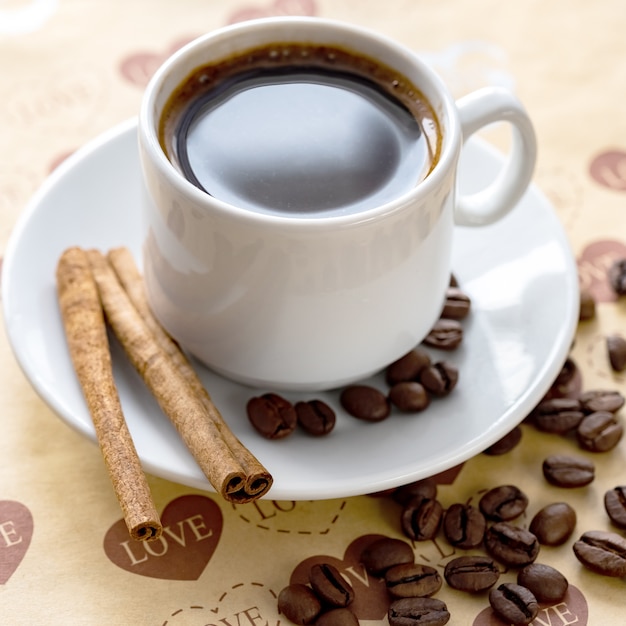 Una taza de café natural en grano y canela.